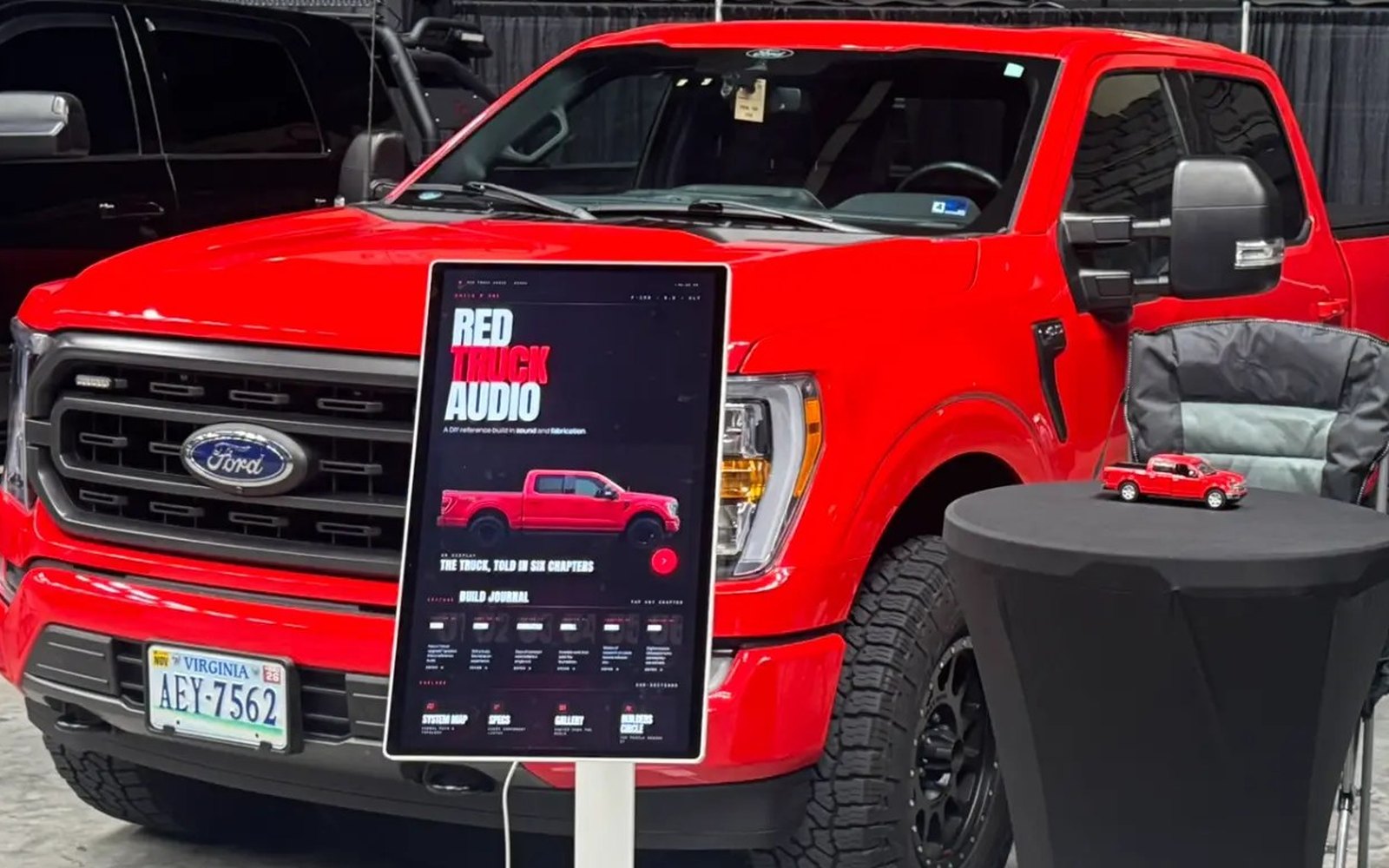 The Red Truck Audio kiosk live on its LG touchscreen at a car-audio SQ competition, next to the red F-150